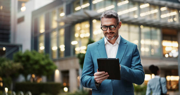 ejecutivo Mature, business and man with tablet outdoor for communication, research and typing email on website. Professional, male manager and digital for networking, contact and task management in urban city