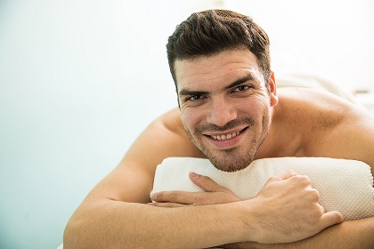 Hispanic man relaxing in a spa Portrait of an attractive young Hispanic man lying on a bed in a spa and smiling